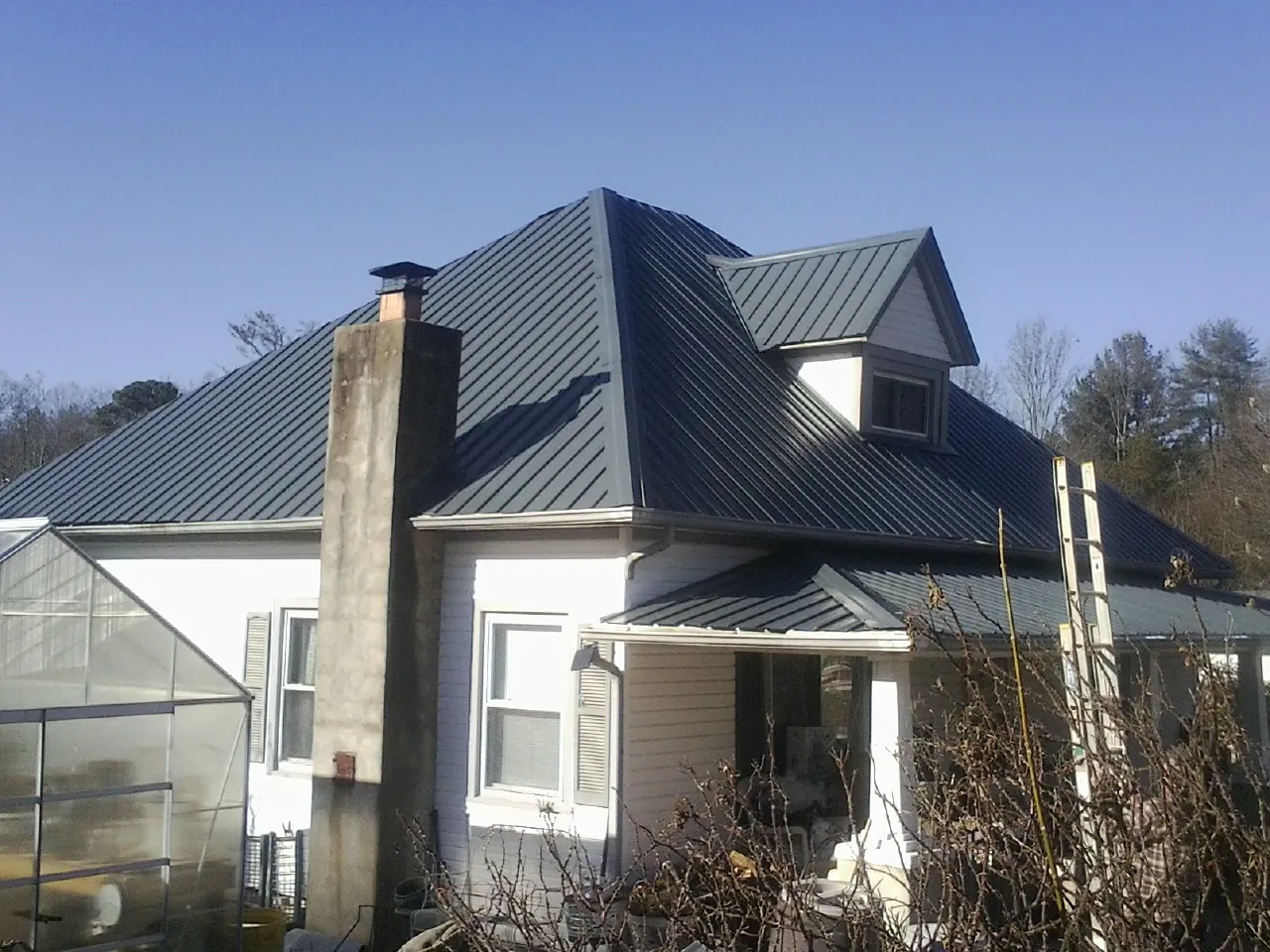 Dark blue standing seam metal roof on a white farmhouse with dormer — Slate & Tile Roof Repair by Roofing Brothers in Fort Jennings