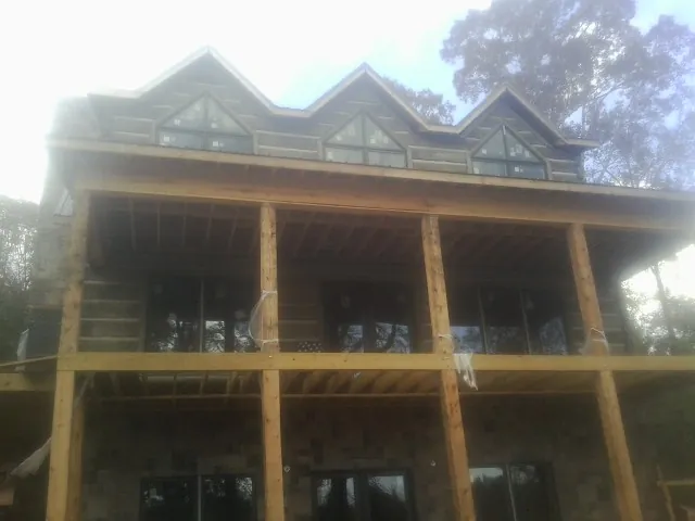 Dormers and porch framing on a large log home under construction — Roof Coating work by our crew in Fort Jennings