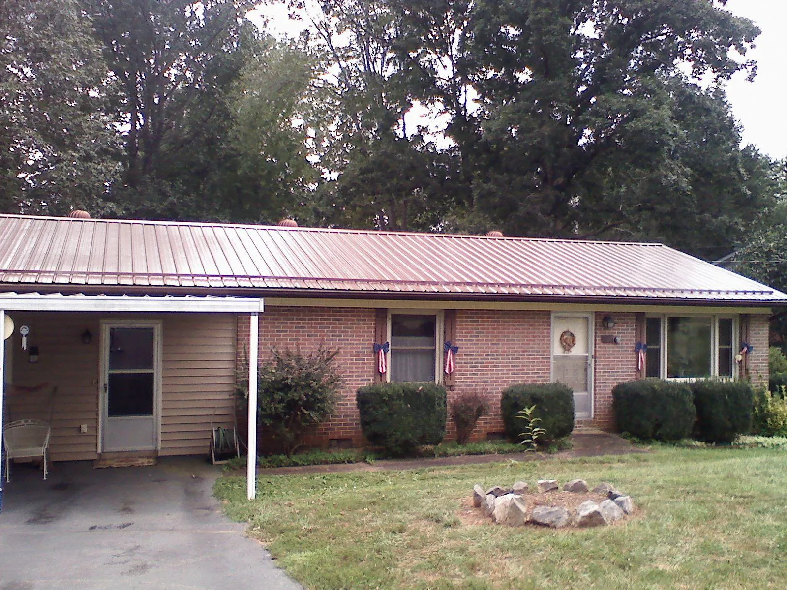 Bronze metal roof and carport on a brick ranch home — Roof Repair work by our crew in Fort Jennings