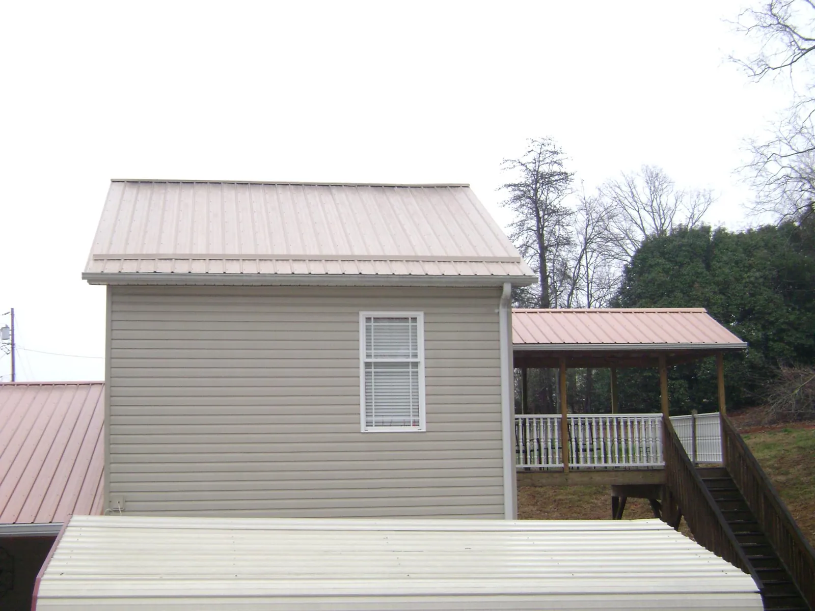 Tan metal roofs on a two story addition and attached porch, from a Roof Replacement job in Fort Jennings