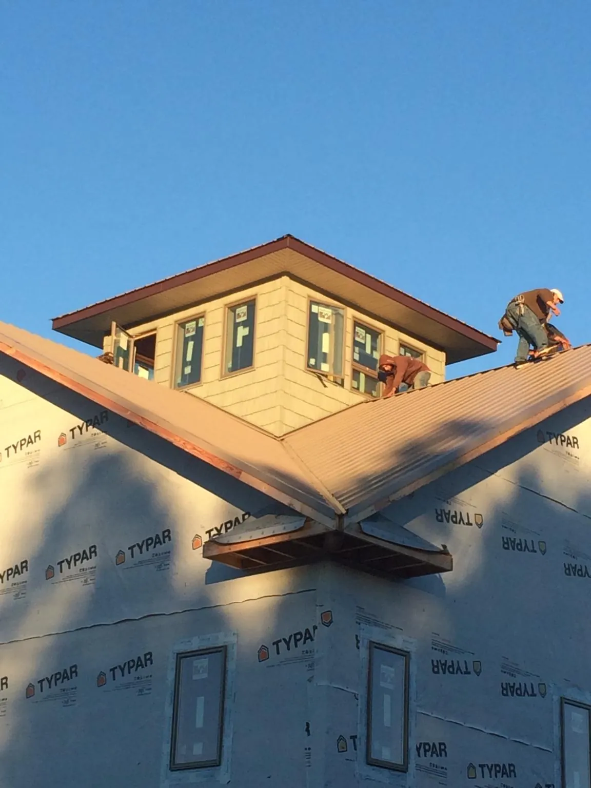 Roofers working around a rooftop cupola on a new metal roof at sunset — Roof Waterproofing in Fort Jennings by Roofing Brothers